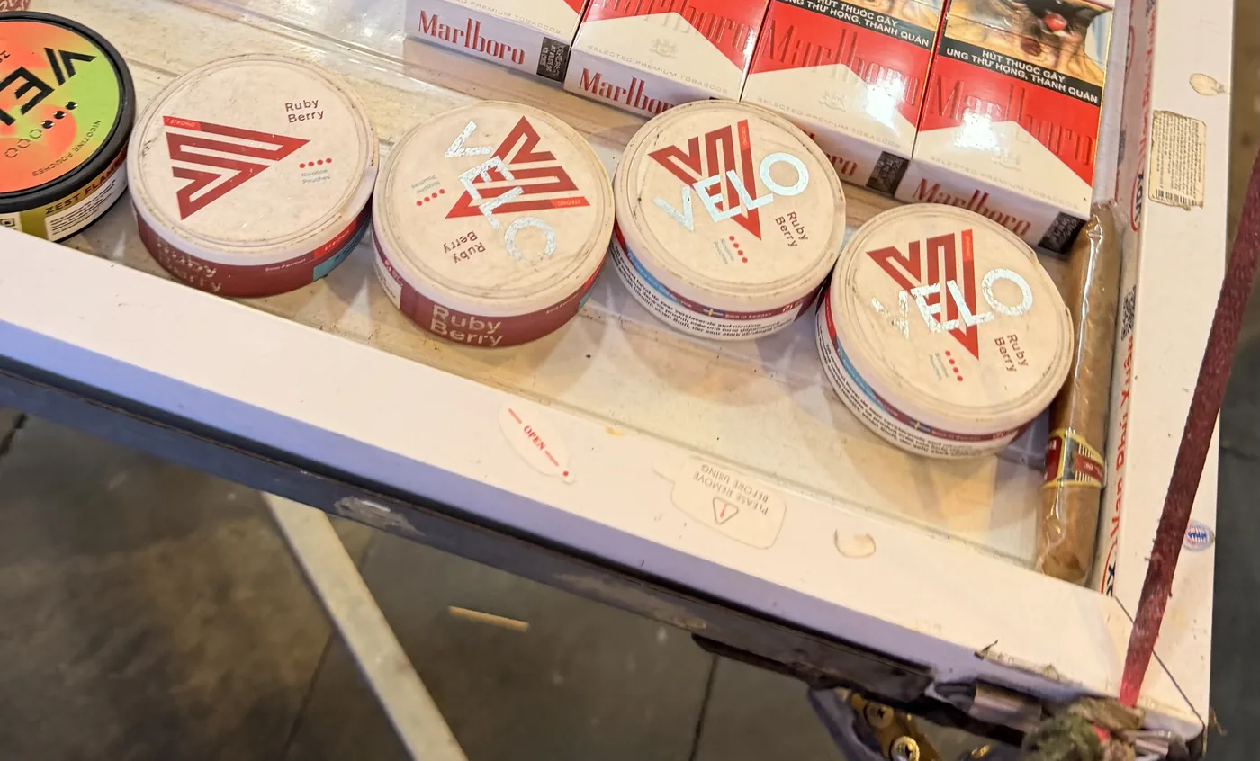 Bốn hộp VELO xếp hàng trên ngăn trưng bày, hộp nào cũng ghi Ruby Berry, mỗi hộp một kiểu logo và bố cục nhãn khác nhau.